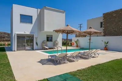 a villa with a swimming pool with chairs and umbrellas at Villa Elios Mare in Asklipiḯon