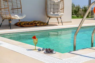 a drink sitting on the edge of a swimming pool at Villa Elios Mare in Asklipiḯon