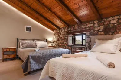 two beds in a room with wooden ceilings at Petronas Land House 2 in Archangelos