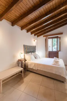 a bedroom with a large bed and a bench at Kantirimi House - A1 in Symi