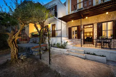 a house with a tree in front of a building at Townhall Apartment in Symi