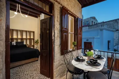 a room with a balcony with a bed and a table at Townhall Apartment in Symi