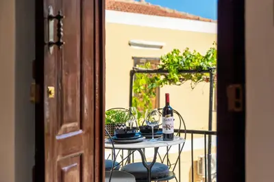 a table with glasses of wine on a balcony at Townhall Apartment in Symi