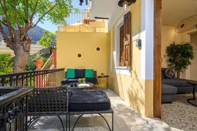 a balcony with chairs and a table and a couch at Townhall Apartment in Symi