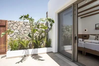 a bedroom with a stone wall and a sliding glass door at CasaCarma V, privates XL-Pool, Boho-Design in Lachania