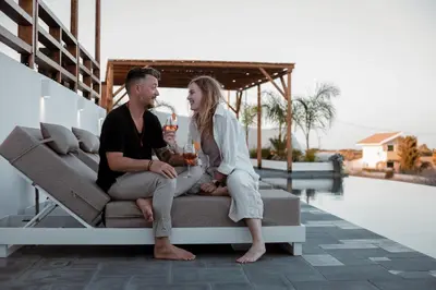 a man and woman sitting on a couch on a patio at CasaCarma IV, private XL Pool, Boho-Design in Lachania