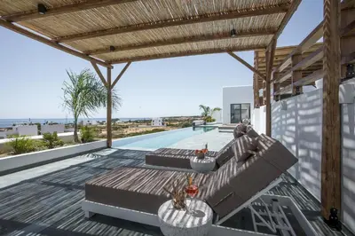 an outdoor patio with a couch and a wooden pergola at CasaCarma IV, private XL Pool, Boho-Design in Lachania