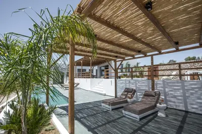 a patio with two chairs and a wooden pergola at CasaCarma IV, private XL Pool, Boho-Design in Lachania