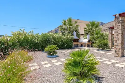 a garden with palm trees and a house at Villa Ariadne Lindos in Pefki Rhodes