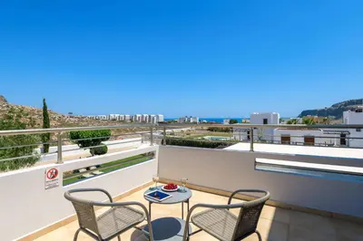 a patio with two chairs and a table on a balcony at Villa Ariadne Lindos in Pefki Rhodes
