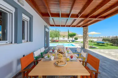 a dining room with a table and chairs and a pool at Villa Ariadne Lindos in Pefki Rhodes