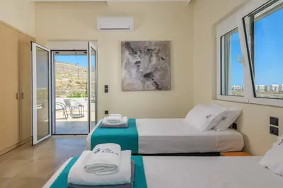 a hotel room with two beds and a balcony at Villa Ariadne Lindos in Pefki Rhodes
