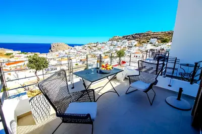 a balcony with a table and chairs and a view of a city at Lindos Beauty in Líndos