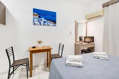 a room with a bed and a table and a desk at Johnhara Studios & Apartments in Ialyssos