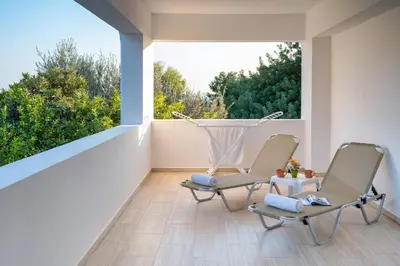 two chairs on a balcony with a large window at Nikolas Apartment in Pefki Rhodes