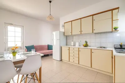 a kitchen with white cabinets and a table and chairs at Nikolas Apartment in Pefki Rhodes