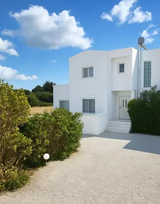a white house with bushes in front of it at Aegean Helios Houses in Gennadi