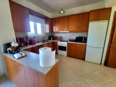 a kitchen with wooden cabinets and a white refrigerator at Aegean Helios Houses in Gennadi