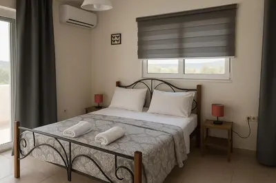 a bedroom with a bed with two pillows and a window at Aegean Helios Houses in Gennadi