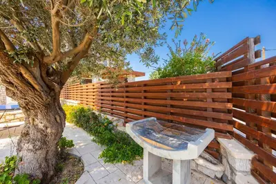 a bench next to a wooden fence with a tree at Villa Ira in Lachania