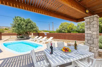 a patio with a table and chairs and a swimming pool at Villa Dias in Lachania
