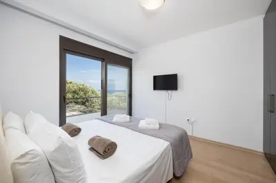 a white bedroom with a bed and a large window at Villa Dias in Lachania