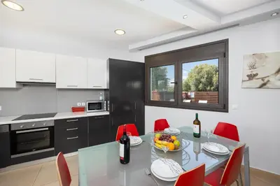 a kitchen with a glass table and red chairs at Villa Dias in Lachania