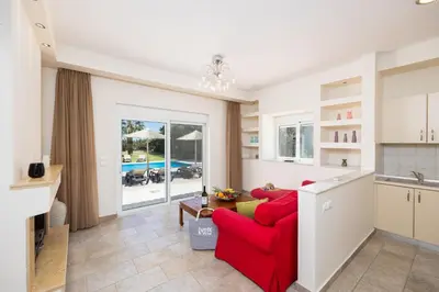 a living room with a red couch and a kitchen at Villa Pelagos Blue in Yennadhion