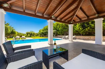 a patio with a table and chairs and a pool at Villa Mediterranean Blue in Yennadhion