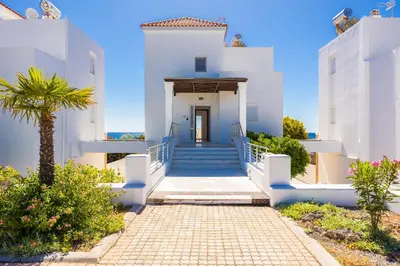a white house with stairs and a palm tree at Villa Mediterranean Blue in Yennadhion