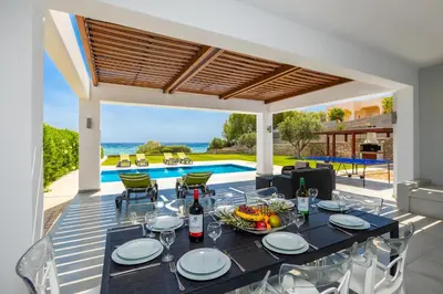a dining table and chairs on a patio with a pool at Villa Dionysos in Lachania