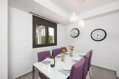 a dining room with a table with purple chairs and clocks at Villa Dionysos in Lachania