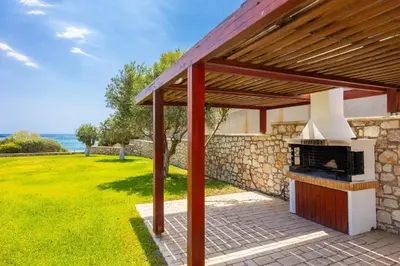 a outdoor kitchen with a stone wall and a wooden pergola at Villa Dionysos in Lachania