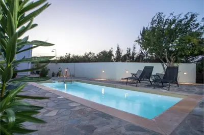a swimming pool with two chairs and a fence at Villa Verona Pool in Lachania