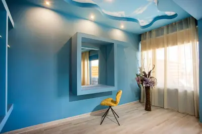 a blue room with a yellow chair and a mirror at Haven Beach in Faliraki