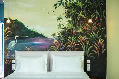 a bedroom with a painting behind a bed with white pillows at Haven Beach in Faliraki