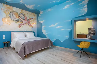 a bedroom with a blue wall with a bed and a mirror at Haven Beach in Faliraki