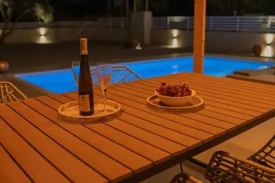 a bottle of wine and a bowl of grapes on a wooden table at Casa Elia Filerimos in Pastida