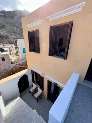 a view of a building with two chairs on a balcony at Pavlos House in Symi