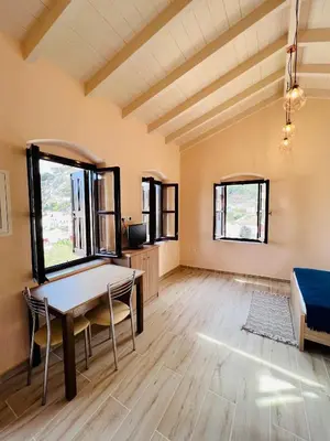 a living room with a table and chairs and windows at Pavlos House in Symi