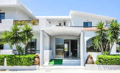a white house with palm trees in front of it at Valentino Hotel in Kremasti