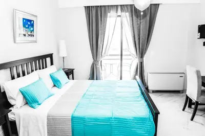 a bedroom with a bed with blue pillows and a window at Valentino Hotel in Kremasti
