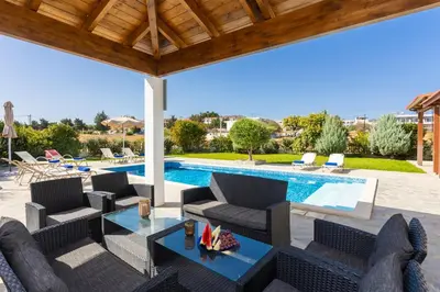 a patio with a table and chairs and a swimming pool at Hermione Villa in Gennadi