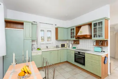 a kitchen with green cabinets and a table with bananas at Hermione Villa in Gennadi