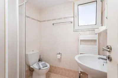 a bathroom with a toilet and a sink and a window at Hermione Villa in Gennadi
