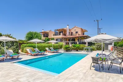 a villa with a swimming pool with chairs and umbrellas at Villa Alnika Acacia by Villa Plus in Lachania