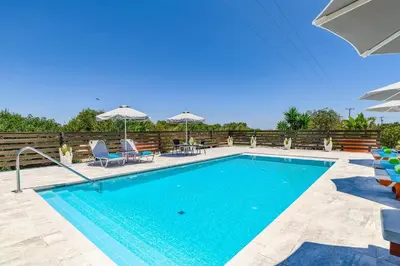 a swimming pool with chairs and tables and umbrellas at Villa Alnika Acacia by Villa Plus in Lachania