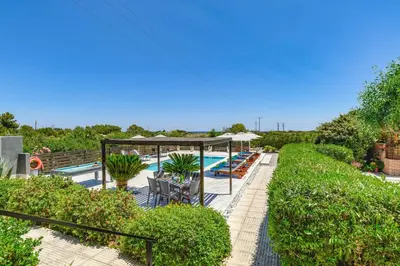a swimming pool with tables and umbrellas and plants at Villa Alnika Acacia by Villa Plus in Lachania