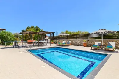 a swimming pool with a table and chairs next to it at Villa Alnika Azalea by Villa Plus in Lachania