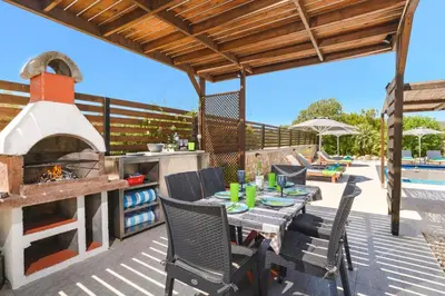 a patio with a table and an outdoor oven at Villa Alnika Azalea by Villa Plus in Lachania